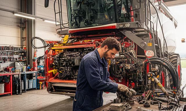 Mecánico agrícola trabajando en el taller con una cosechadora de gran tamaño